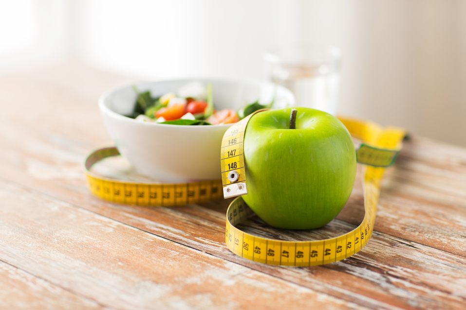 to illustrate weight loss balloon procedures and diet, a picture of green apple and measuring tape with salad on wooden table